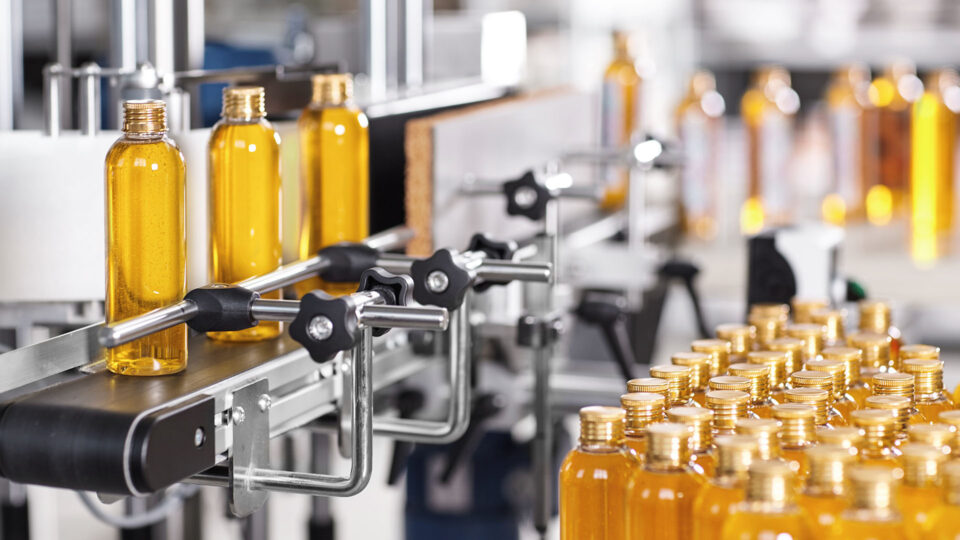A photograph of yellow glass bottles on a production line.