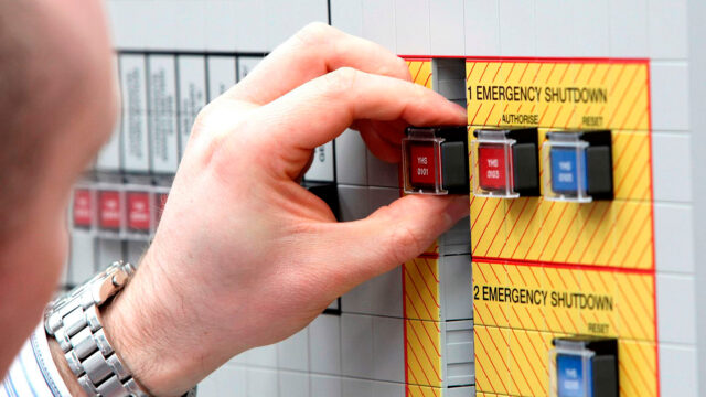 A man touching an emergency shutdown button.