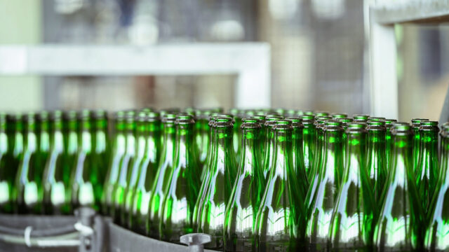 A photograph of green glass bottles on a production line.