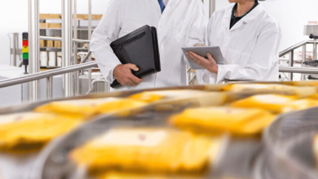 Two people standing near a production line on a tablet.