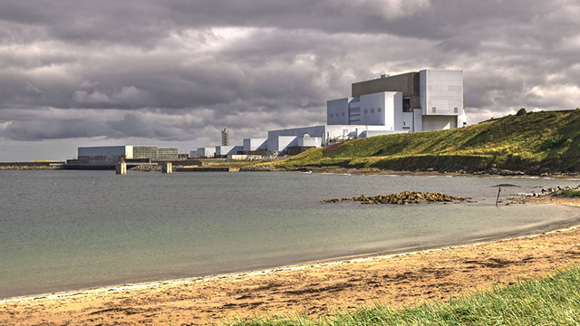 A photograph of a shoreline with an industrial building in the background.